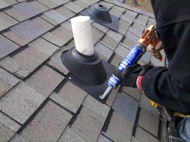 Homeowner caulking around roof PVC pipe.
